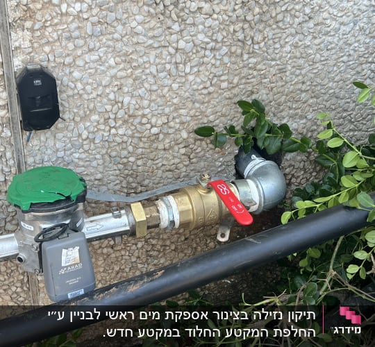 צנרת מים עם ברז אדום על קיר חיצוני
